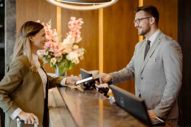 Woman making payment through NFC technology on mobile phone in the hotel